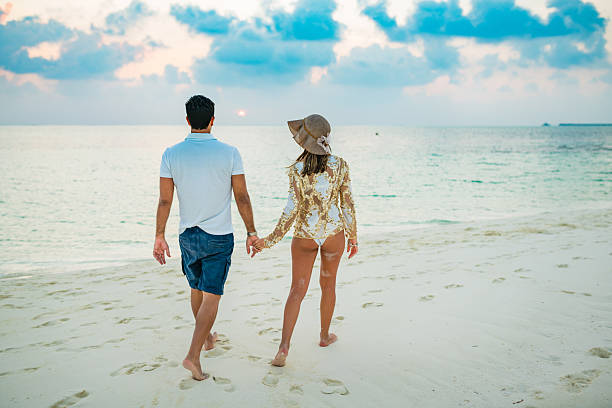 Young couple enjoying walking watching sunset at Dhiffushi Holiday island, South Ari atoll, Maldives. Model and Property released. Hi resolution photo.