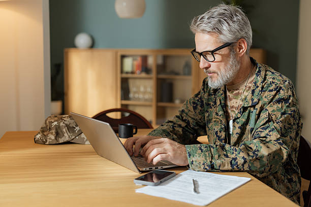 istock Veteran in camouflage clothes using a laptop at home 2250798208