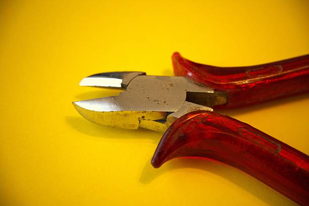 Red pliers placed on a bright yellow background in close-up view with Copy Space for design and concepts.