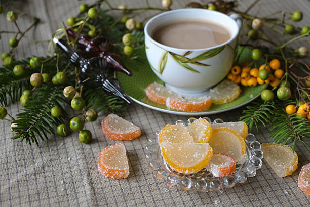 Holiday still life with a cup of coffee, colorful citrus jelly candies and evergreen decorations. Warm seasonal composition with natural textures and classic Christmas elements. Perfect for winter celebrations and cozy lifestyle themes.