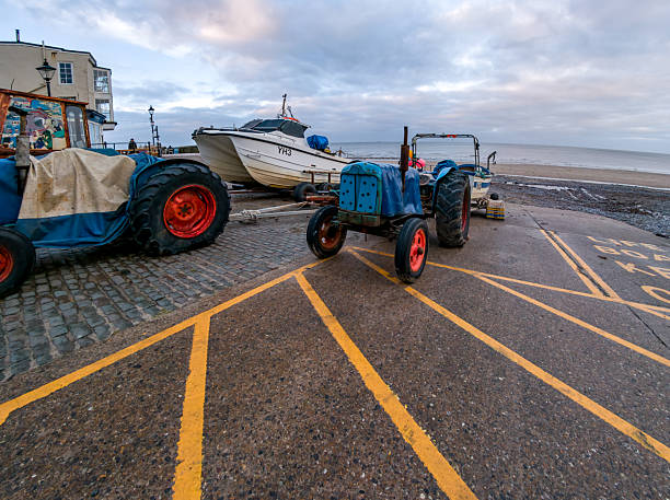 Tractors with a boat on the beach at Cromer, North Norfolk, UK. December 2023