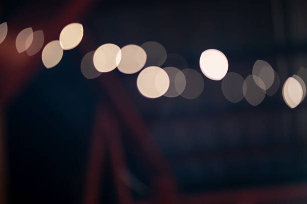 Soft, out-of-focus golden lights form circular bokeh shapes against a dark background. The gentle glow contrasts with the deep surrounding tones, creating a dreamy, atmospheric effect. The scene conveys warmth, calmness, and a festive or contemplative mood.