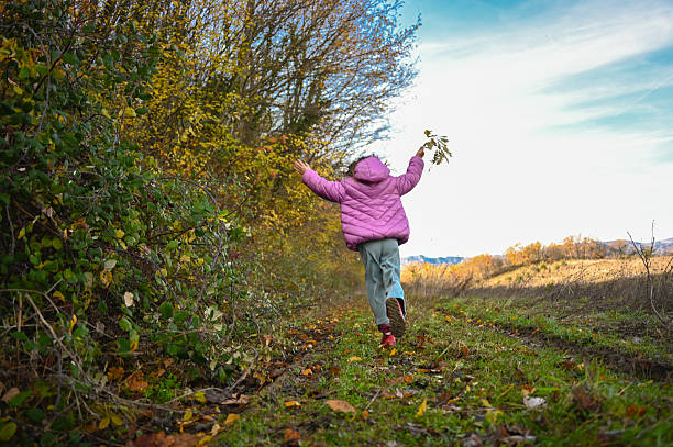 Two happy little girls running down a hill