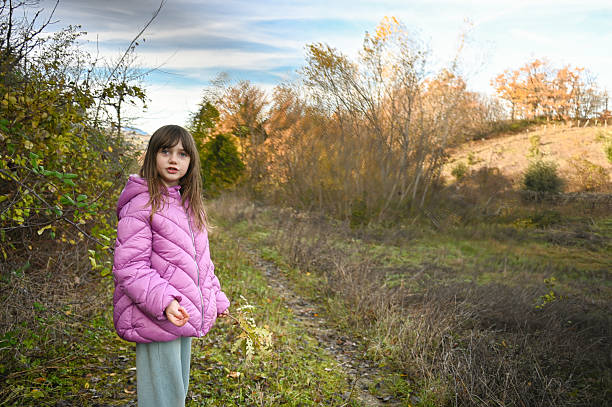 Young girl walking outdoors, enjoying autumn nature on a peaceful rural path
