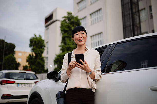 istock Young Japanese woman leaning against her car while using her smartphone. 2250814863