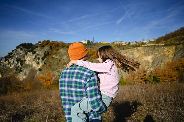 Father holding his young daughter in a loving embrace outdoors during autumn