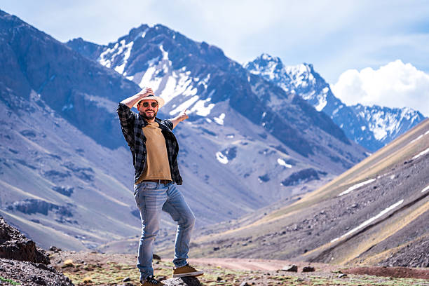Young man enjoying the incredible landscapes of Mendoza, Argentina. Tourist enjoying the Andes Mountains in Mendoza, Argentina. Tourist pointing towards a huge mountain in Mendoza