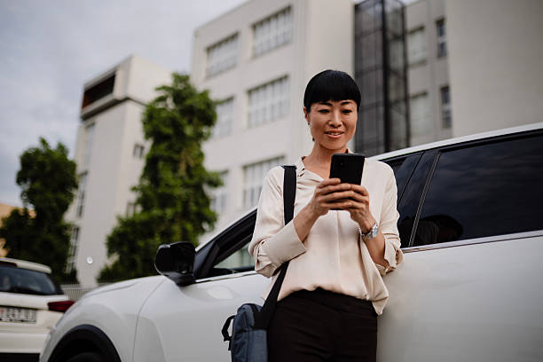 istock Young Japanese woman leaning against her car while using her smartphone. 2250815409