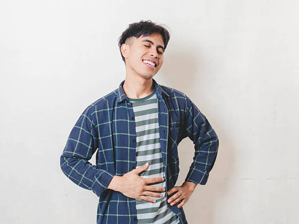 istock Asian man smiling with a relieved expression while touching his belly against a clean white backdrop, showing comfort, satisfaction, and positive emotion. 2250817975