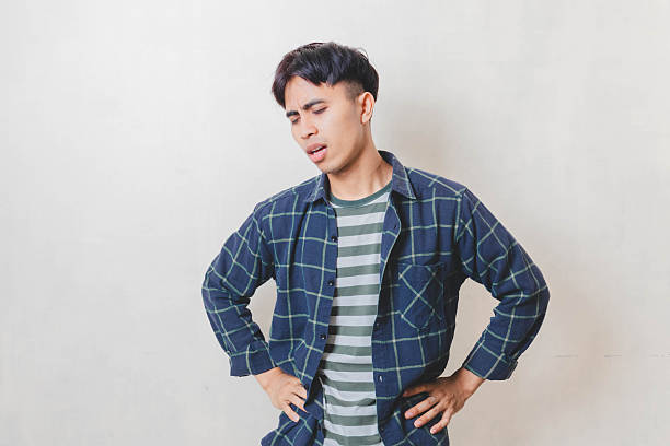 istock Tired young Asian man standing showing exhausted and stressed expression while looking down on a white isolated background. 2250818968