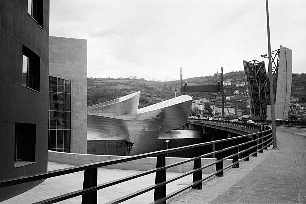 Bilbao-Spain / 9 September 2024: Outside the Guggenheim museum. Looking at the impressive facade with surrounding. Postmodern architecture. Coverd with scale-shaped titanium plates.