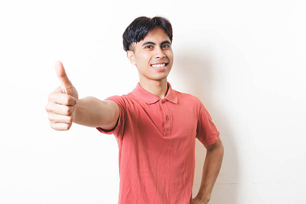 istock Smiling man giving a thumbs-up gesture, showing approval and positive expression on a clean bright background. 2250823747