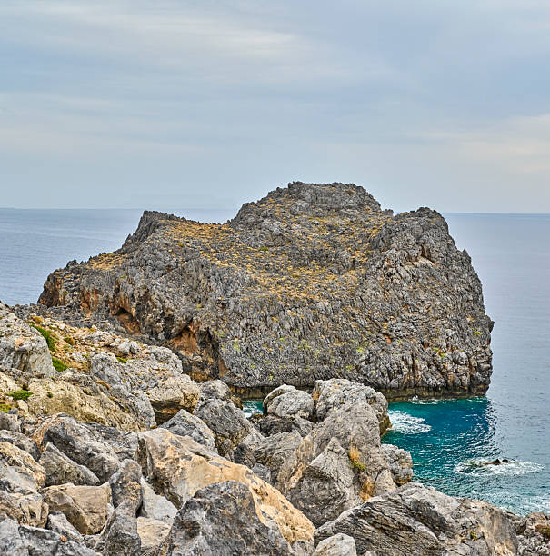 Crete, Greece coastal path along rugged cliffs at sunset. A serene Mediterranean landscape with rocky terrain, low vegetation, and a calm sea to the left. Perfect for travel, nature, hiking, and scenic imagery celebrating coastal beauty and peaceful sunset moments in Greece.