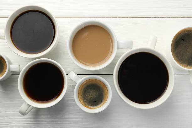 istock Different coffee drinks in cups on white wooden table, flat lay 2250835565