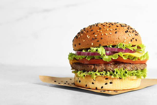 istock Burger with delicious patty on light table, space for text 2250836420