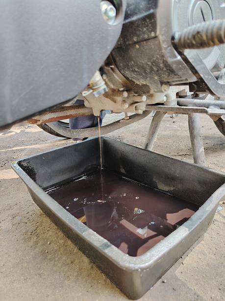 The messy process of draining old lubricant from a vehicle's engine at a workshop.
