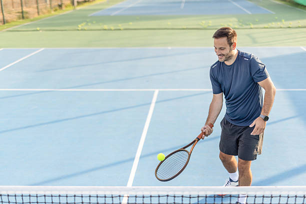 istock Man skillfully executes low tennis shot under clear sunny skies 2250840248