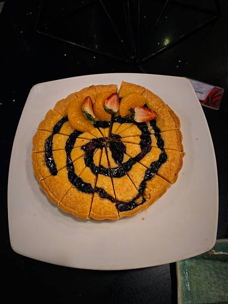 Gourmet dessert featuring a large, round French Toast or Thick Waffle, sliced into wedges like a pizza and drizzled with a rich chocolate or dark berry sauce swirl.