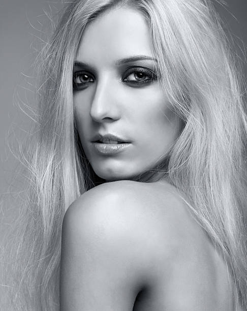 Monochrome portrait of blonde young woman on gray background