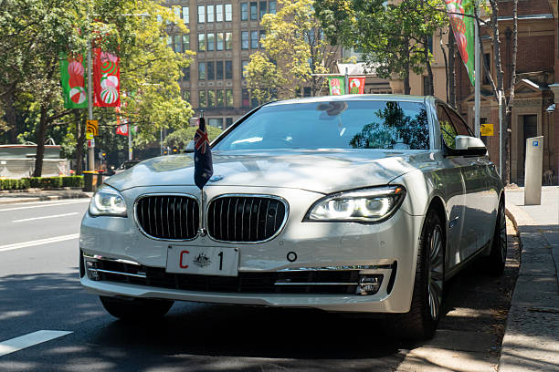 The Australian Prime Minister’s BMW 7 Series vehicle parked on St James Road near Macquarie Street in the central business district of Sydney. The Prime Minister, the Hon Anthony Albanese MP, is at a nearby function.  The “C” in the number plate stands for “Commonwealth”.  In the left background is Hyde Park, while in the right background is a department store on Elizabeth Street. Centrepoint Tower is reflected on the windscreen and bonnet. Christmas banners hang from street light poles. This image was taken on a hot and sunny afternoon on 9 December 2025.