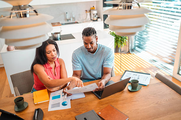 istock Confident Couple Reviewing Financial Documents in Sunlit Kitchen 2250874451