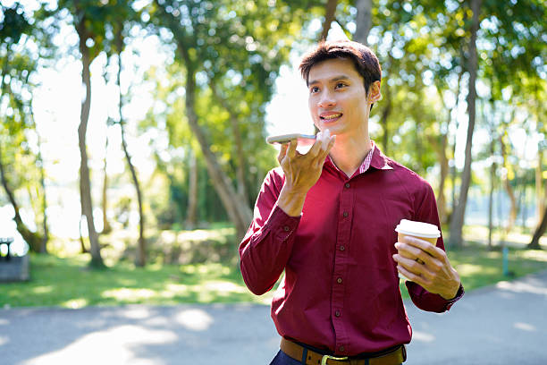 istock Young asian man with takeout coffee communicating on smartphone at urban park, blank space 2250886079