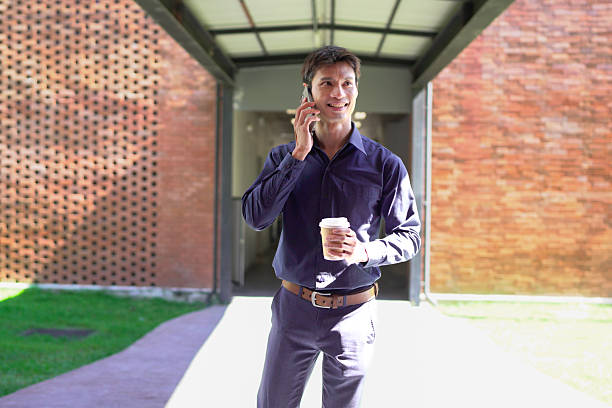 istock Young business man calling talking on the mobile phone on coffee break from office building outside. Businessman walking on street commute lifestyle. 2250886276