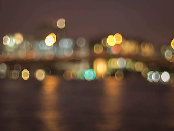 An abstract, out-of-focus image of a city skyline at night, with vibrant, glowing bokeh lights shimmering on the water.