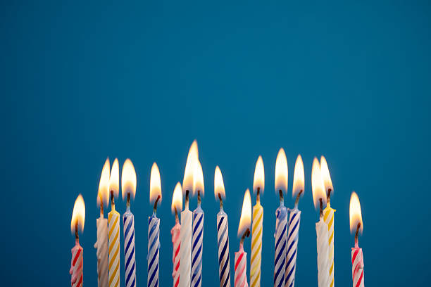 istock Lit multicolored birthday candles over blue background creating warm festive glow, with copy space for message or design. Perfect for birthday party invitations or greetings. 2250887786