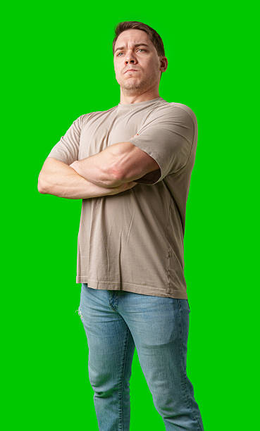 istock Confident man standing with crossed arms in front of bright green backdrop 2250889155