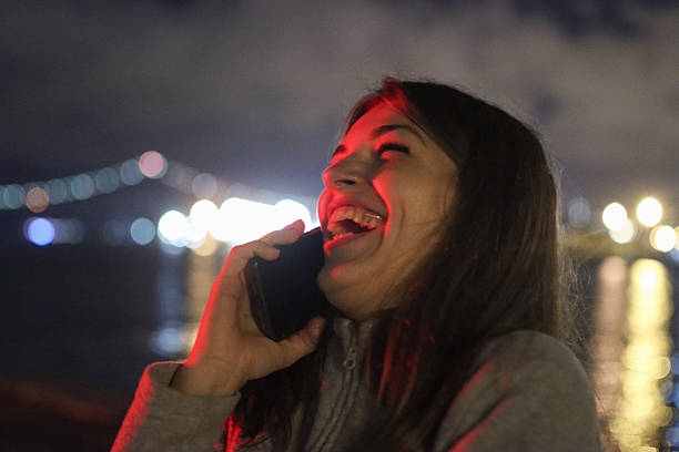 istock Joyful young woman laughing on smartphone at night 2250889684
