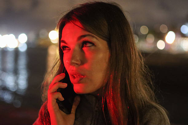 istock Woman talking on phone bathed in red light at night 2250891216
