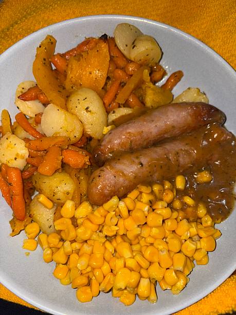 Family meal of sausage roast potatoes butternut squash carrots sweetcorn and gravy