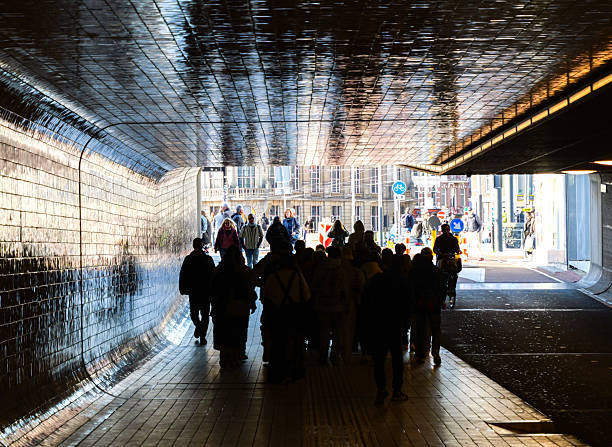 People walking in the train station tunnel towards the city and work in Amsterdam, the Netherlands.