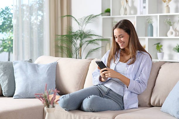 istock Happy woman in blue using cell phone on a couch at home 2250903091