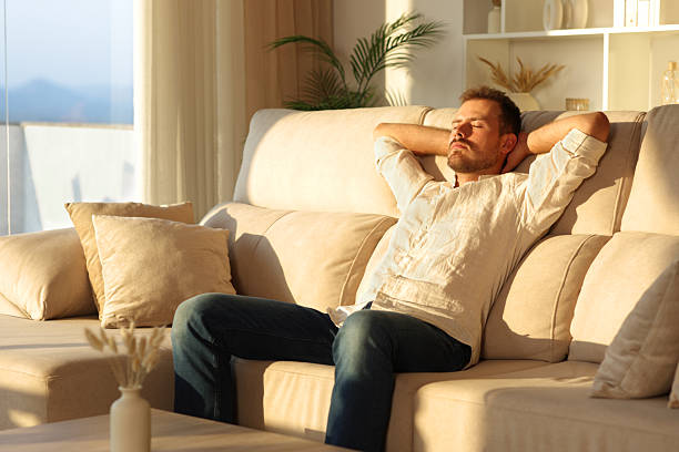 istock Relaxed man at sunset at home resting sitting on a sofa 2250903416