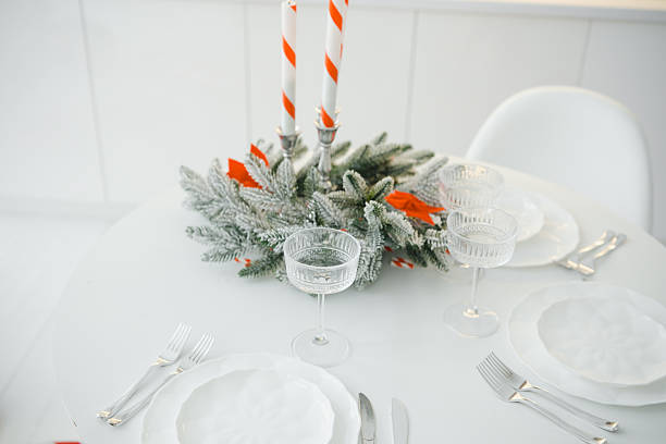 Festive table setting with evergreen centerpiece, candles, and elegant glassware, ready for celebration