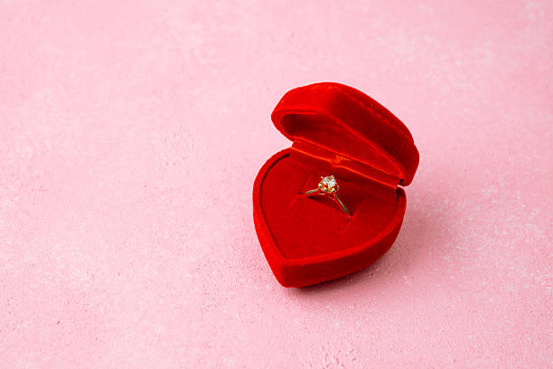 istock Diamond ring in red heart box on pink background 2250903668