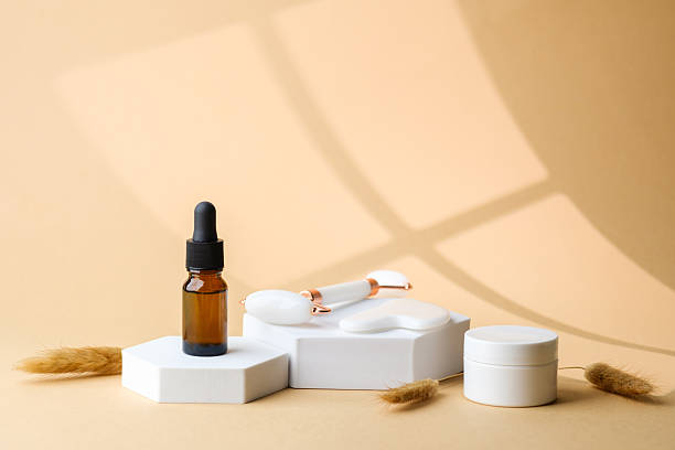 istock Brown glass dropper bottle placed on white pedestal with jade roller and gua sha stone 2250903710
