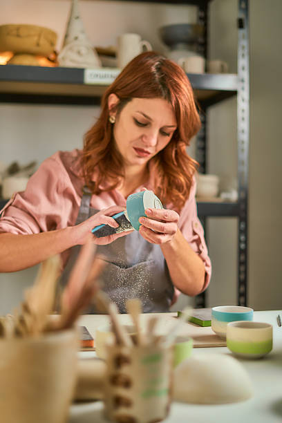 istock Female Artist Sculpting a Ceramic Mug in a Busy Pottery Studio, Focused and Creative 2250911907