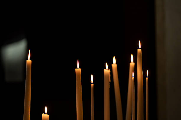 istock Burning candles glowing in the darkness inside a quiet church interior. 2250914577