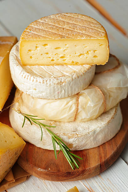 Delicious selection of artisanal cheeses displayed on wooden board with rosemary
