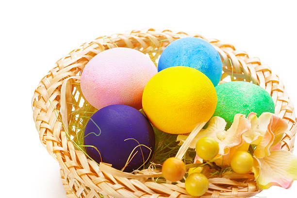Colorful Easter eggs in a woven basket with floral accents on a white background