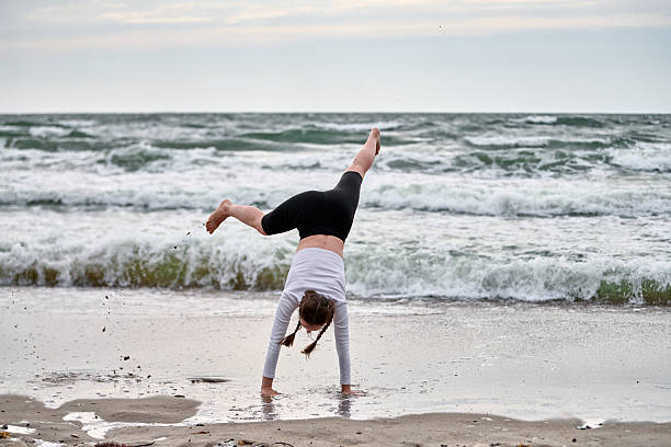 istock Young female performs cartwheel by baltic sea shore 2250917198
