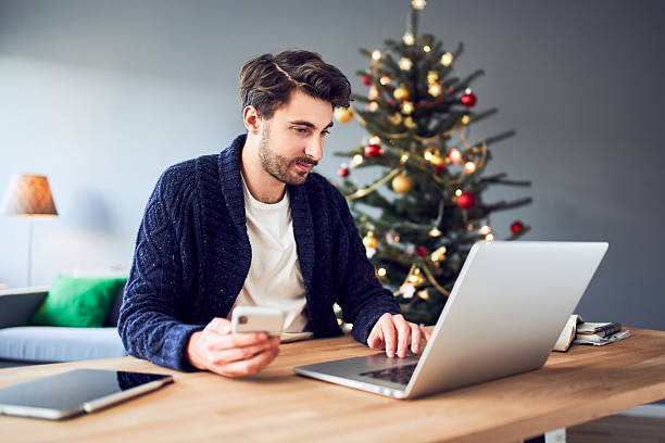 istock Man paying with mobile phone for Christmas shopping using laptop at home 2250918782