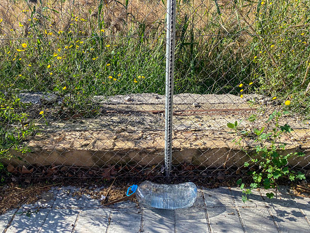 High angle view of a plastic water bottle thrown on the sidewalk next to vacant lot in the city of Valencia, Spain