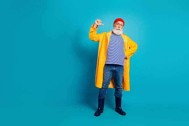 istock Man in yellow raincoat with striped shirt poses confidently in blue studio 2250922905