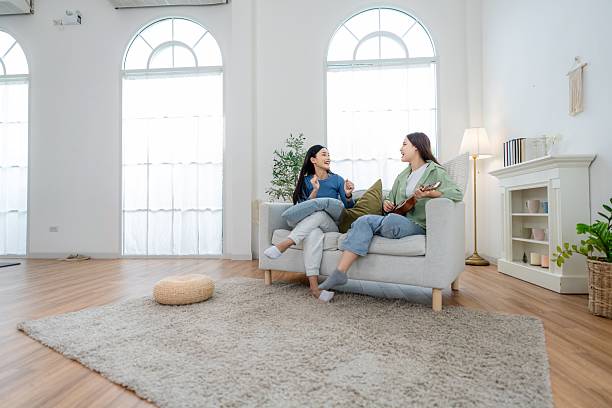 istock Two friends sit on couch talking casually in a bright living room with soft light and plants in the background 2250925097