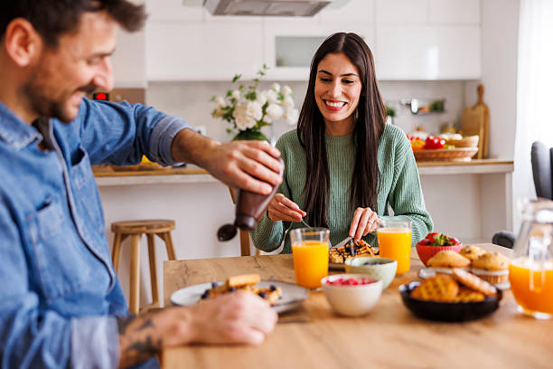 istock Couple putting chocolate topping on waffles while having breakfast at home 2250926971
