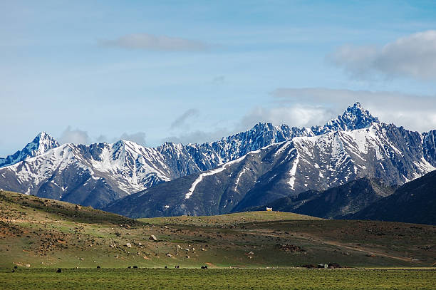 istock Majestic snow-capped mountains with green grassy foreground under clear sky 2250929470